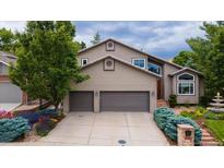 Two story home with two car garage, complemented by colorful landscaping and mature trees at 16458 W Ellsworth Dr, Golden, CO 80401
