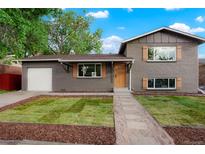 Charming gray brick home with manicured front lawn, garage, and wooden accents at 14544 March Dr, Denver, CO 80239