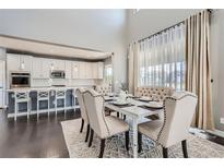 Bright dining area with a large window, stylish furnishings, and hardwood floors adjacent to a modern kitchen at 14881 Rider Pl, Parker, CO 80134