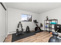 Bright exercise room featuring laminate floors, weights, shelving, and an exercise bike at 6940 E Girard Ave # 210, Denver, CO 80224