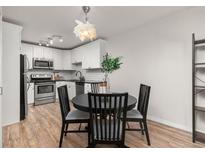 Modern kitchen features stainless steel appliances, white cabinets, and a cozy dining area with a round table at 6940 E Girard Ave # 210, Denver, CO 80224