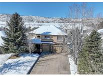 Stunning two-story home with a three-car garage and snow-covered roof, set against a beautiful mountain backdrop at 10914 W Coco Pl, Littleton, CO 80127