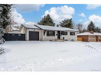 Snow covered yard, charming ranch home with updated exterior and a black fence at 12029 W Dakota Dr, Lakewood, CO 80228