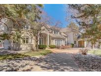 Elegant two-story home featuring a brick driveway, manicured lawn, and charming architectural details at 7 Mockingbird Ln, Cherry Hills Village, CO 80113
