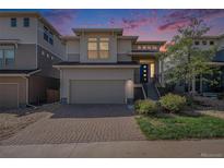 Beautiful two story home with brick driveway, garage and modern architecture under a vibrant sunset sky at 3116 Jonquil St, Castle Rock, CO 80109