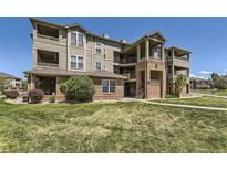 Multi-level condo building shows manicured lawn, brick accents, and upper level balconies at 12818 Ironstone Way # 101, Parker, CO 80134