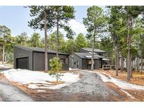 Exterior view of a modern home with a detached garage, surrounded by trees and some snow on the ground at 19185 Shadowood Dr, Monument, CO 80132