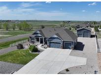 Stunning aerial view of a blue home featuring a long driveway and a detached garage at 31353 E 163Rd Ave, Hudson, CO 80642