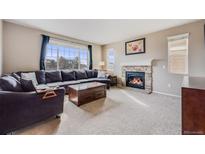 Cozy living room with a stone fireplace, large window, and comfortable seating at 10294 E Telluride Ct, Commerce City, CO 80022