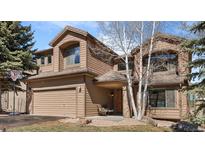 Charming brown home features a two-car garage, covered entryway, and mature trees in the front yard at 24037 Deer Valley Rd, Golden, CO 80401