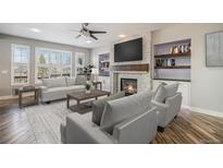 Cozy living room with a fireplace, recessed lighting, and large windows that flood the room with natural light at 4431 W Jamison Pl, Littleton, CO 80128
