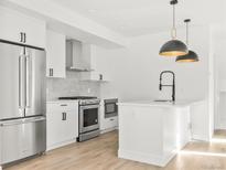 Modern kitchen boasts stainless steel appliances, white cabinets, a functional island, and contemporary hanging light fixtures at 1346 N Knox Ct, Denver, CO 80204