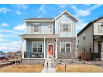 Charming two-story home featuring stone accents, covered porch, and inviting orange front door at 21209 E 62Nd Ave, Aurora, CO 80019