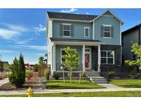 Charming two-story home with light blue siding, stone accents, landscaped yard and a welcoming front porch at 21209 E 62Nd Ave, Aurora, CO 80019