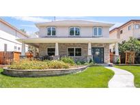 Charming two-story home featuring stone accents, a covered porch with seating, and a beautifully landscaped front yard at 1644 S Garfield St, Denver, CO 80210