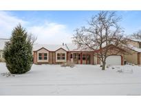 Ranch-style home with snow-covered front yard, attached garage, and mature trees at 8111 S Marion Ct, Centennial, CO 80122