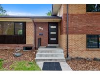Charming brick home featuring a modern front door with glass accents and well-manicured landscaping at 9025 W 4Th Ave, Lakewood, CO 80226