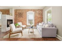 Comfortable living room showcases exposed brick wall, fireplace, and large windows at 3864 Osceola St, Denver, CO 80212