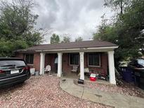Charming brick home featuring a covered front porch with white pillars and a cozy, inviting entrance at 1900 Quebec St, Denver, CO 80220