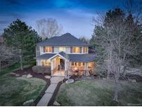 Inviting two-story home featuring a covered front porch, well-manicured lawn, and mature trees at 6724 S Yates Ct, Littleton, CO 80128