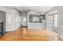 Open-concept living and kitchen area featuring hardwood floors, modern lighting, and stainless steel appliances at 7680 Elmwood St, Littleton, CO 80125