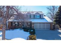 Two-story house with attached garage, snow-covered yard, and mature trees at 14734 E Evans Pl, Aurora, CO 80014