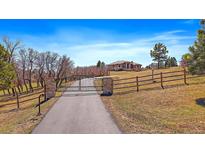Scenic view of a stunning estate with a gated entrance and a long driveway leading to the beautiful home at 1552 Colt Cir, Castle Rock, CO 80109