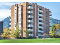 Multi-story brick building featuring balconies and mountain views set against a bright blue sky at 850 20Th St # 503, Boulder, CO 80302