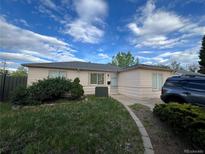 Cozy one-story home with a well-maintained lawn and mature landscaping, complemented by a clear sky backdrop at 1082 Geneva St, Aurora, CO 80010