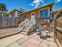 Charming brick home with a white front door, stairs, and a cozy patio set, perfect for outdoor relaxation at 4418 W 11Th Ave, Denver, CO 80204