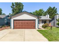 Charming single-story home featuring a large garage, well-maintained lawn, and colorful flower beds at 3735 S Lewiston St, Aurora, CO 80013