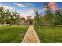 Charming ranch-style home with stone walkway and mature trees, offering a warm and inviting curb appeal at 10380 W Warren Ave, Lakewood, CO 80227