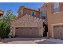 Inviting home exterior with stone accents, brown garage door, and well-maintained landscaping at 9546 Firenze Way, Highlands Ranch, CO 80126