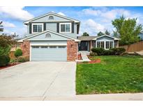 Charming two-story home featuring blue siding, a brick facade, and a well-manicured lawn at 705 Prairie Ridge Rd, Highlands Ranch, CO 80126
