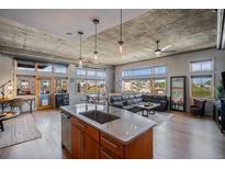 Spacious living room featuring an island kitchen, hardwood floors, exposed concrete ceilings and plenty of natural light at 1925 W 32Nd Ave # 404, Denver, CO 80211