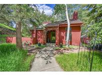 Charming red home with a landscaped front yard and a stone pathway leading to the inviting front door at 23626 Genesee Village Rd, Golden, CO 80401