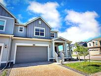 Charming two-story home featuring a gray exterior, brick driveway, and attached garage at 700 Lillibrook Pl, Erie, CO 80026
