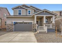Charming two-story home featuring stone accents, a covered porch, and a gray garage door at 24736 E Evans Dr, Aurora, CO 80018
