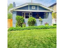 Charming blue home featuring a well-manicured lawn and lush landscaping in the front yard at 3341 Newton St, Denver, CO 80211
