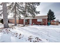 Brick ranch home with snowy front yard and mature trees at 2391 Lansing St, Aurora, CO 80010