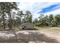 Charming exterior view with a well-maintained lawn, siding, a sun room, and mature trees in a serene setting at 4295 Picutis Rd, Indian Hills, CO 80454