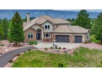 Charming home featuring a stone facade, three-car garage, and beautiful landscaping at 1127 Buttermilk Rd, Larkspur, CO 80118
