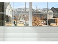 View of the neighborhood street, with snow-capped mountains in the distance, as seen from inside the home at 9305 Gore St # A, Arvada, CO 80007