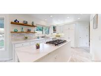 Bright kitchen with white cabinets, stainless steel appliances, and a center island with cooktop at 10886 Pheasant Run, Littleton, CO 80125