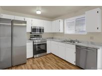 Well-lit kitchen with stainless steel appliances, white cabinetry, and marble-pattern countertops at 16651 E Arizona Pl, Aurora, CO 80017