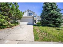 Charming two-story home featuring a two-car garage, well-maintained lawn, and mature trees on a sunny day at 11305 W Crestline Dr, Littleton, CO 80127