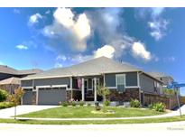 Charming single-story home featuring a well-manicured lawn, stone accents, and an attached two-car garage at 599 Fall River Ct, Brighton, CO 80601