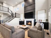 Bright and airy living room with a fireplace, soaring ceilings, and elegant black iron stair railings at 7012 S Undergrove Way, Aurora, CO 80016