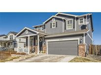 Charming two-story home featuring a welcoming front porch, grey siding and an attached two-car garage at 5657 Jaguar Way, Lone Tree, CO 80124