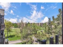 Scenic view of the golf course from a balcony shows lush green grass, tall trees, and blue skies with white clouds at 14001 E Marina Dr # 606, Aurora, CO 80014